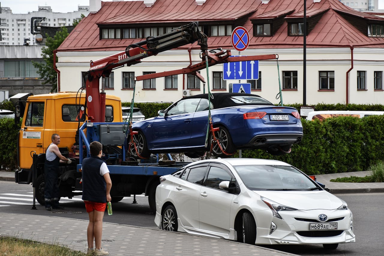 our-journey-01 Towing a blue Audi convertible in a bustling city street.