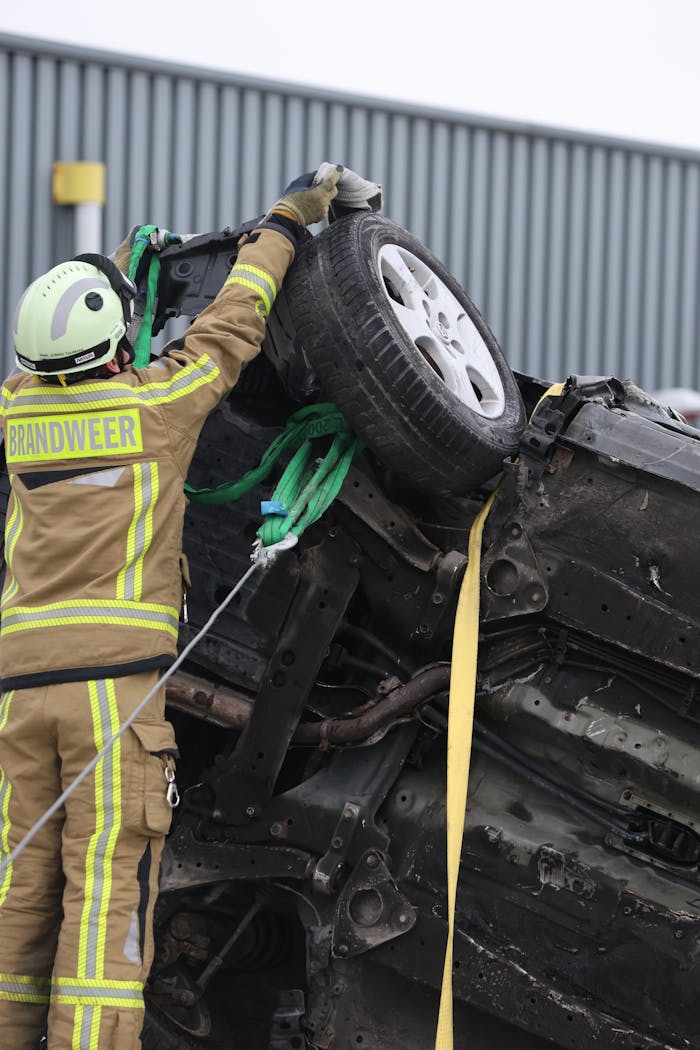 services-01 Firefighter in protective gear secures overturned car at an accident scene with ropes and equipment.