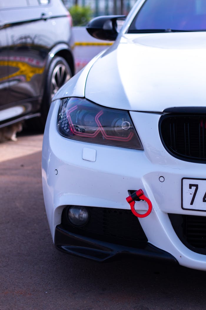 our-journey-02 Detailed view of a white cars front headlight and bumper in daylight, ideal for automotive themes.